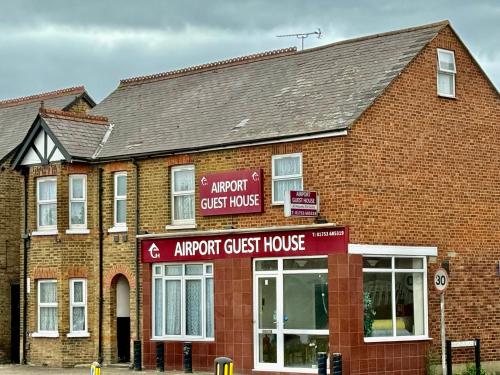 an arrow guest house in front of a brick building at Airport Guest House in Slough