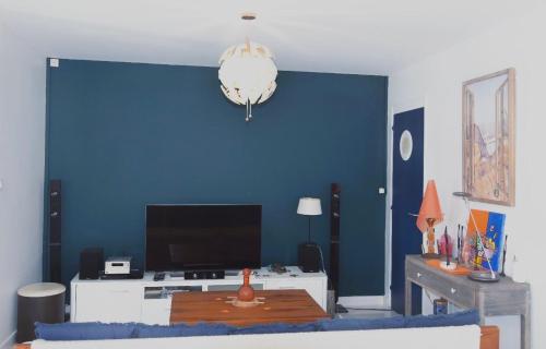 a living room with a blue wall and a table at Brise Marine in Le Marin
