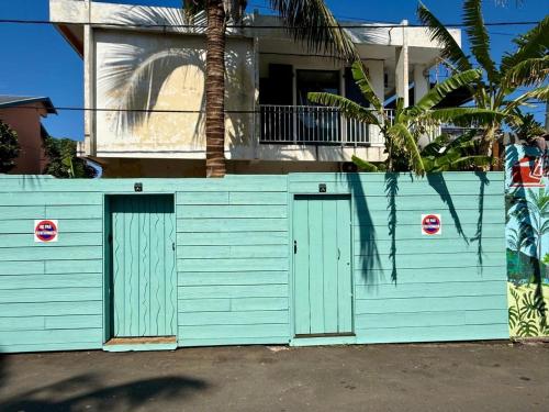a blue garage with two doors in front of a house at Les Cazes Terre Sainte 1 - Proche CHU in Saint-Pierre