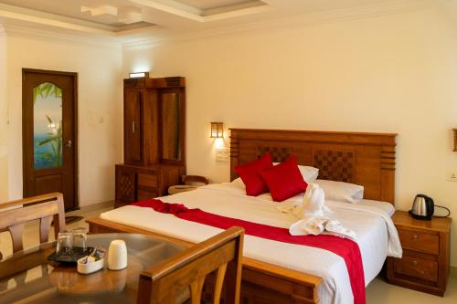 a bedroom with a large bed with red pillows and a table at Seven Springs Plantation Resort in Munnar