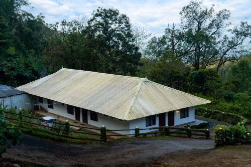 a white house with a metal roof and a fence at Seven Springs Plantation Resort in Munnar