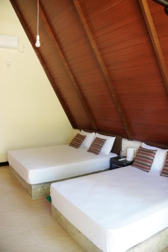 two beds in a room with wooden ceilings at Coco Breeze Cabanas - free Airport pick up or drop off in Katunayake