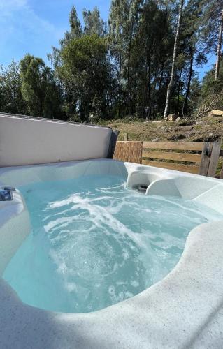 a large hot tub with blue water in a backyard at Kaoglen Apollo-Hot tub-Cairngorms-Pet friendly in Balnald