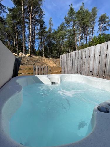 a hot tub in a backyard with a wooden fence at Kaoglen Apollo-Hot tub-Cairngorms-Pet friendly in Balnald