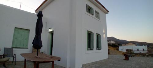 a white building with a table and an umbrella at Liopi Village Andros in Órmos