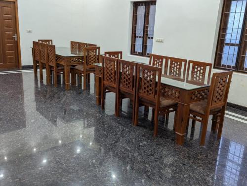 a row of wooden tables and chairs in a room at Chithira House Tranquil Holiday Home in Alleppey
