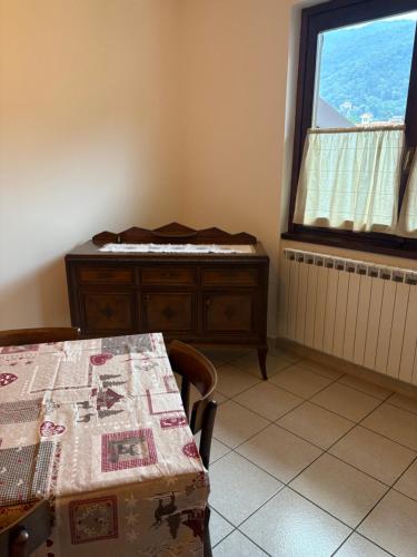 a room with a table and a bed and a window at Civico 16 in Asso