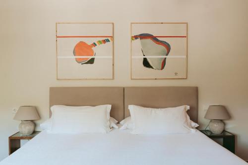 a bedroom with a bed with two pictures on the wall at Rondaia, a Winery & Fincahotel-Agroturismo in Tramuntana in Esporles