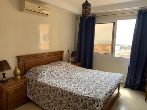 a bedroom with a bed and a window with blue curtains at Appartement OCEAN VIEW in Tamraght Ouzdar
