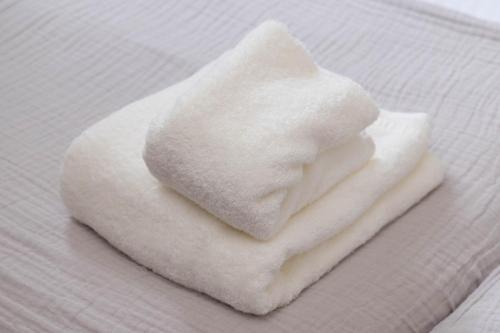 a pile of white towels sitting on a bed at FukuokaKukouGoodStay in Fukuoka