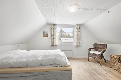 a bedroom with a bed and a chair and a window at 0194-Romo-Rabjergvej-76 in Kongsmark