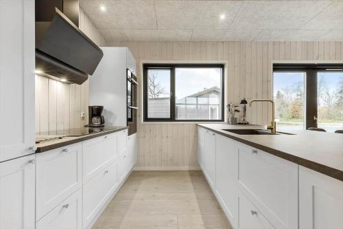 a large kitchen with white cabinets and a sink at 8902-Allingabro-Dalgardsvej-4 in Allingåbro
