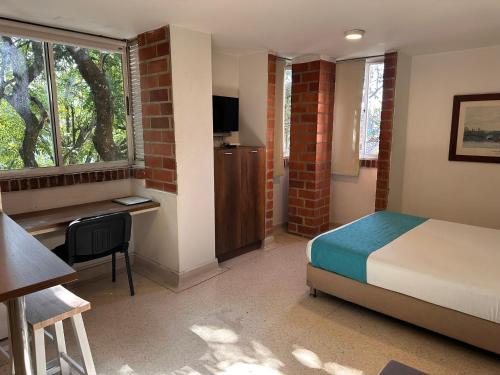 a bedroom with a bed and a desk and a window at Amoblados Medellín Laureles in Medellín