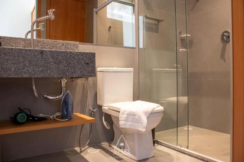 a bathroom with a toilet and a glass shower at Villa Naluri - Seu Refúgio a 50 metros da praia em Japaratinga in Japaratinga