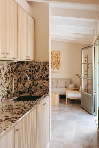 a kitchen with marble counter tops and a living room at Rondaia, a Winery & Fincahotel-Agroturismo in Tramuntana in Esporles
