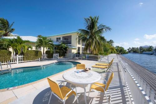 ジョージ・タウンにあるSnug Harbour View Condo #8のスイミングプールのそばにパティオ(テーブル、椅子付)