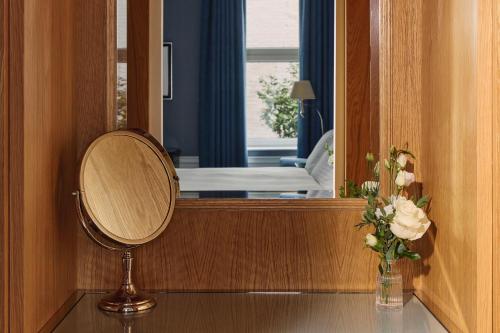 a mirror in a room with a vase of flowers at The Connaught, Maybourne in London