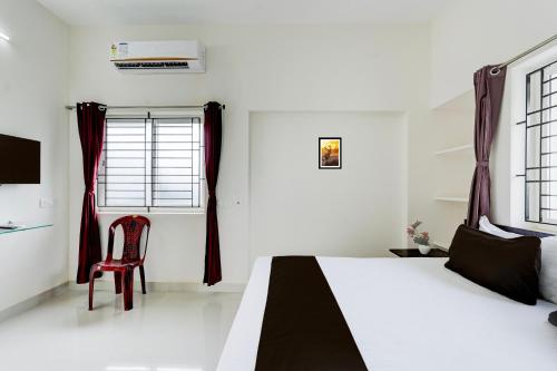 a white bedroom with a bed and a red chair at Hotel O Elegant Residency Vandalur Zoo in Chennai