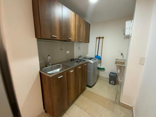 a small kitchen with wooden cabinets and a sink at Amoblados Medellín Laureles in Medellín