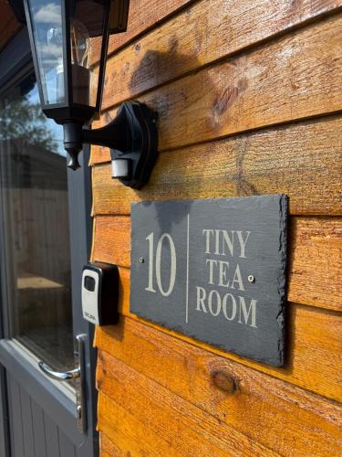 a sign on the side of a house with a tea room at The Tiny Tea Room in Ridingmill
