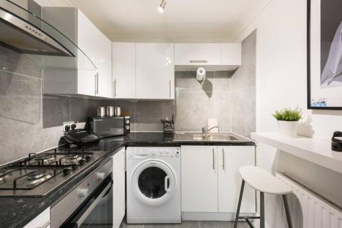 a kitchen with a washing machine and a stove at SleepOver Wembley in London
