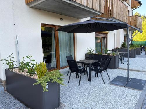 a patio with a table and chairs and an umbrella at Studio Mavis in Kašperské Hory