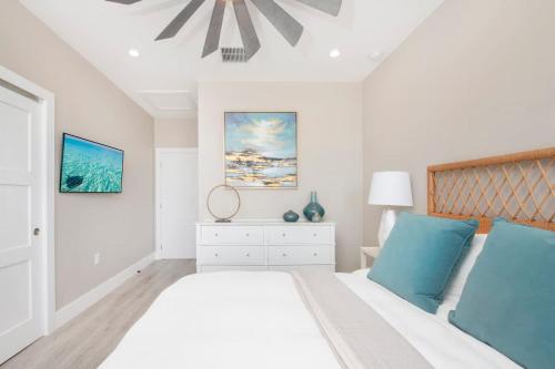 a white bedroom with a large bed with blue pillows at Mahogany Villa 2-A / 4BR in Omega Gardens