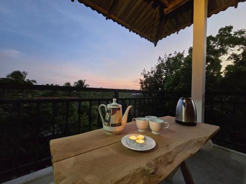 a wooden table with a tea pot and cups on it at Whispering Wave Tangalle in Tangalle
