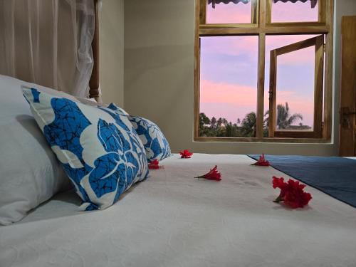 a bed with red flowers on it with a window at Whispering Wave Tangalle in Tangalle