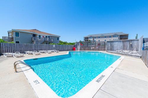 a swimming pool with chairs and a fence at Dune View TB3E - Cozy 1BR Condo with Loft, Pool, Pet-Friendly in Kill Devil Hills