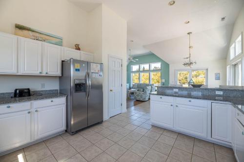 a kitchen with white cabinets and a stainless steel refrigerator at D0597 Dune Fine - Duck Landing Amenities, Pool, Hot Tub, Pets OK, Keyless! in Duck