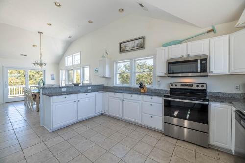 a kitchen with white cabinets and a stove top oven at D0597 Dune Fine - Duck Landing Amenities, Pool, Hot Tub, Pets OK, Keyless! in Duck