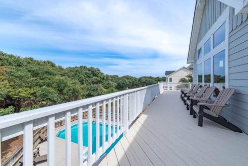 a balcony with chairs and a swimming pool on a house at D0597 Dune Fine - Duck Landing Amenities, Pool, Hot Tub, Pets OK, Keyless! in Duck