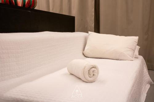 a white towel laying on a white bed with pillows at Villa Naluri - Seu Refúgio a 50 metros da praia em Japaratinga in Japaratinga