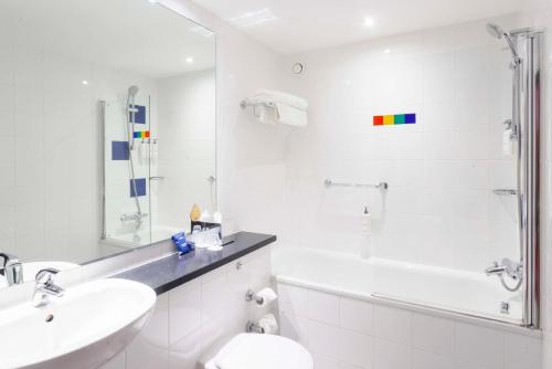 a white bathroom with a sink and a tub and a toilet at Park Inn by Radisson Aberdeen in Aberdeen