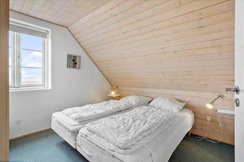 a bed in a room with a wooden wall at 0286-Romo-Sonder-Frankel-34 in Havneby