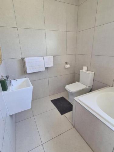 a white bathroom with a sink and a toilet at Karoo Retreat- Self Catering Villas and Guest House in Oudtshoorn