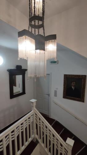 a staircase with a chandelier and a picture of a man at Penzion Nad Kašnou in Kašperské Hory