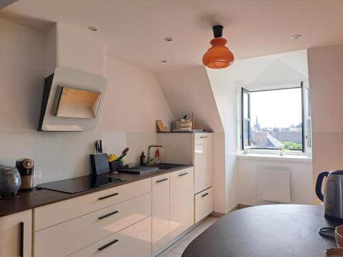 a kitchen with white cabinets and a window at Loft d'architecte - vue sur port et deco vintage in Paimpol