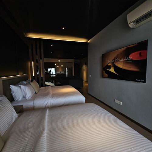a hotel room with two beds and a tv on the wall at Black Martini Premium Suite in Tanjong Tokong