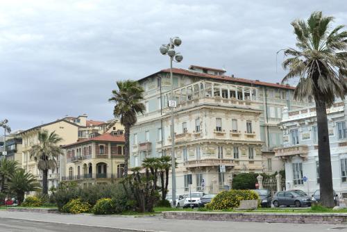 a building with palm trees in front of a street at Cozy Valeria's Room in Camaiore