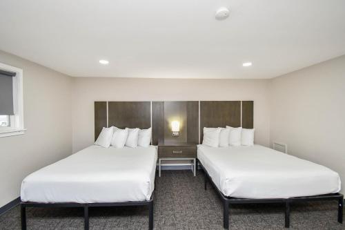 two beds in a hotel room with white sheets at Settle Inn in Sioux Falls