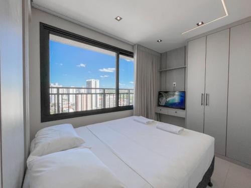 a bedroom with a white bed and a large window at Flat Espaçoso com Uma Bela Vista e 2 Quartos in Campo Grande