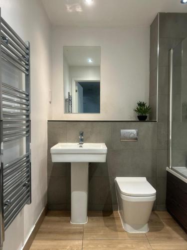 a bathroom with a sink and a toilet and a mirror at Near Old Trafford & Media City 2BR Flat in Manchester