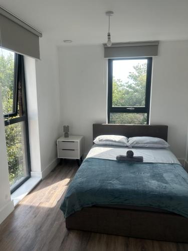 a bedroom with a large bed with two windows at Near Old Trafford & Media City 2BR Flat in Manchester