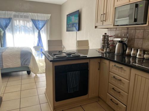a kitchen with a stove top oven next to a bed at Apartment in Bloemfontein in Bloemfontein