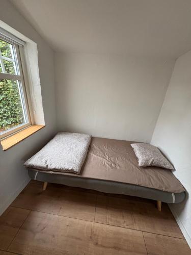a bed in a corner of a room with a window at Gäststugan in Ystad