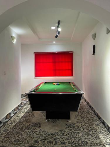 a pool table in a room with a red wall at Ungess Global Ventures in Iju Junction