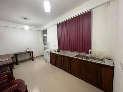 Crimple cottage في نوارا إليا: مطبخ مع حوض وستارة حمراء