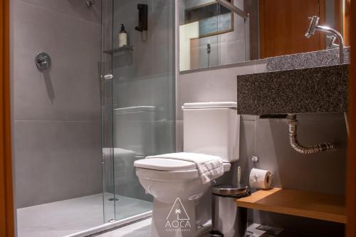 a bathroom with a toilet and a glass shower at Villa Naluri - Seu Refúgio a 50 metros da praia em Japaratinga in Japaratinga